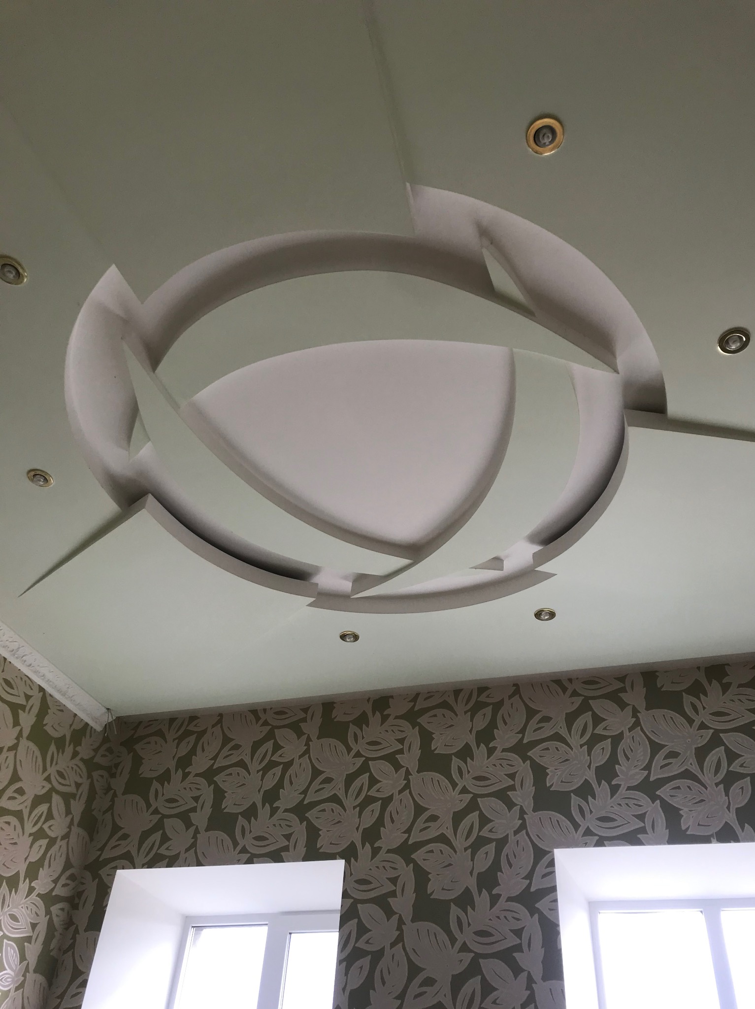 Oryginalny sufit podwieszany z gips-kartonu z oświetleniem punktowym w kształcie okręgu, Wrocław. Nowoczesne wykończenie wnętrza z dekoracyjną ścianą.