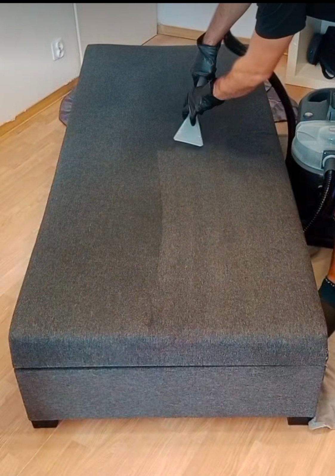 Czyszczenie tapicerki sofy metodą ekstrakcyjną. Widoczny efekt czyszczenia: jaśniejsza, odświeżona powierzchnia po prawej stronie.