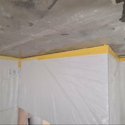 Remonty Wojciech - Przygotowanie do malowania: ściany i sufit zabezpieczone folią i taśmą malarską. Surowy sufit z widocznymi śladami prac wykończeniowych. Ochrona przed zabrudzeniami.