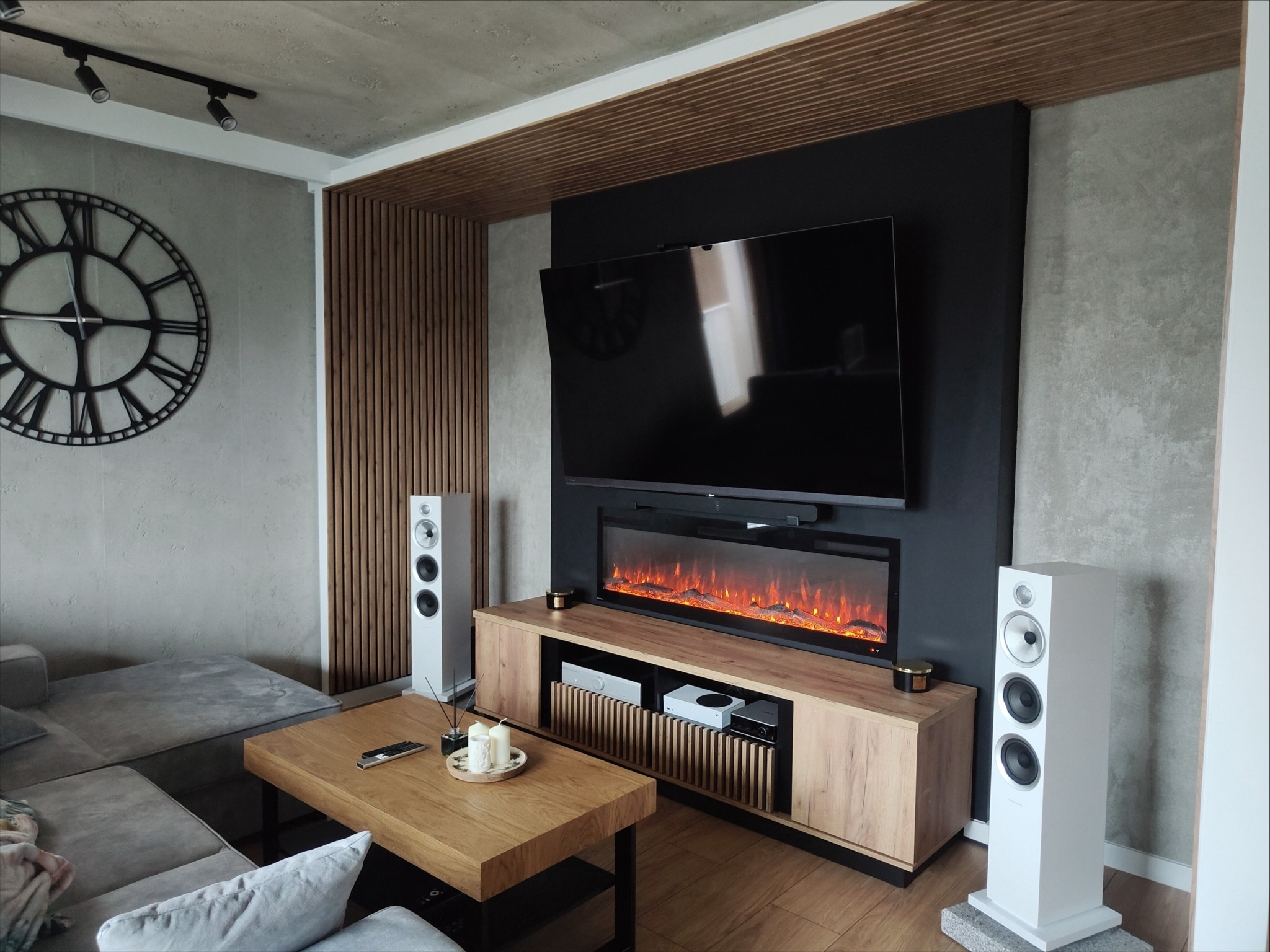 Stylowe wykończenie salonu w Redzie: ściana TV z elektrycznym kominkiem, drewniane panele i nowoczesne głośniki. Nowoczesny design i dbałość o detale.