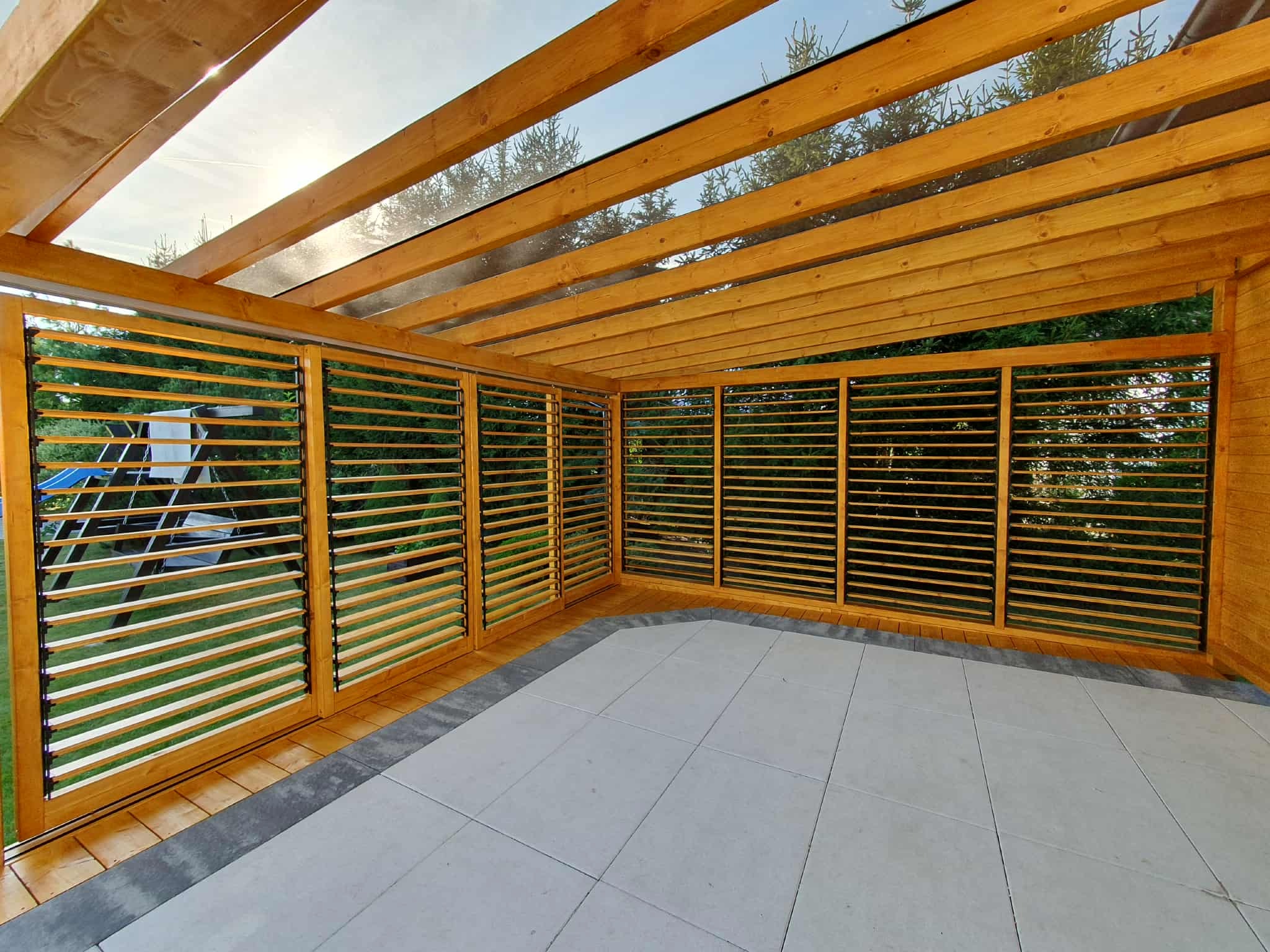 Nowoczesna, drewniana konstrukcja z żaluzjowymi ścianami i przeszklonym dachem w Połczynie-Zdroju. Widok na ogród przez szczeliny.