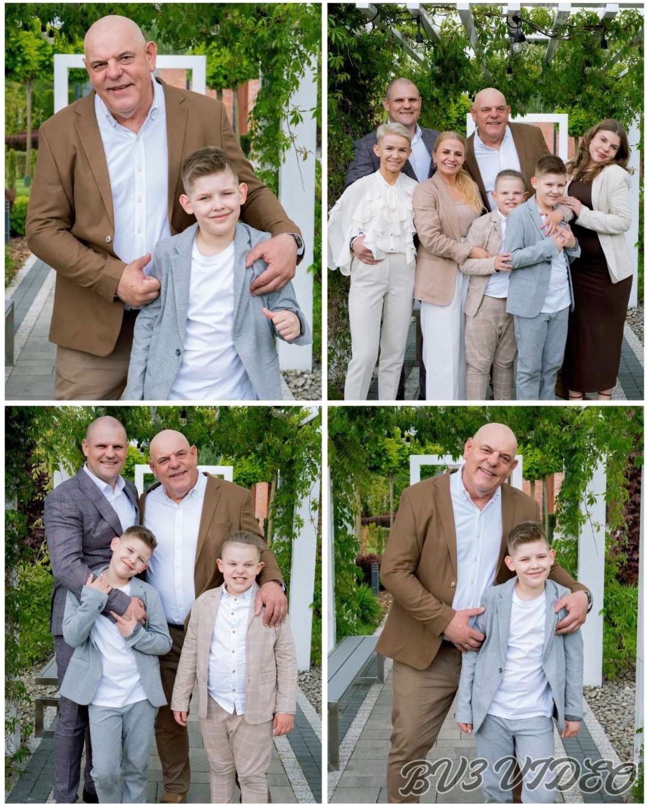 Uśmiechnięta rodzina w eleganckich strojach pozuje na tle zieleni. Mężczyźni w garniturach, chłopcy w marynarkach, kobiety w sukienkach i bluzkach. Radosna atmosfera.