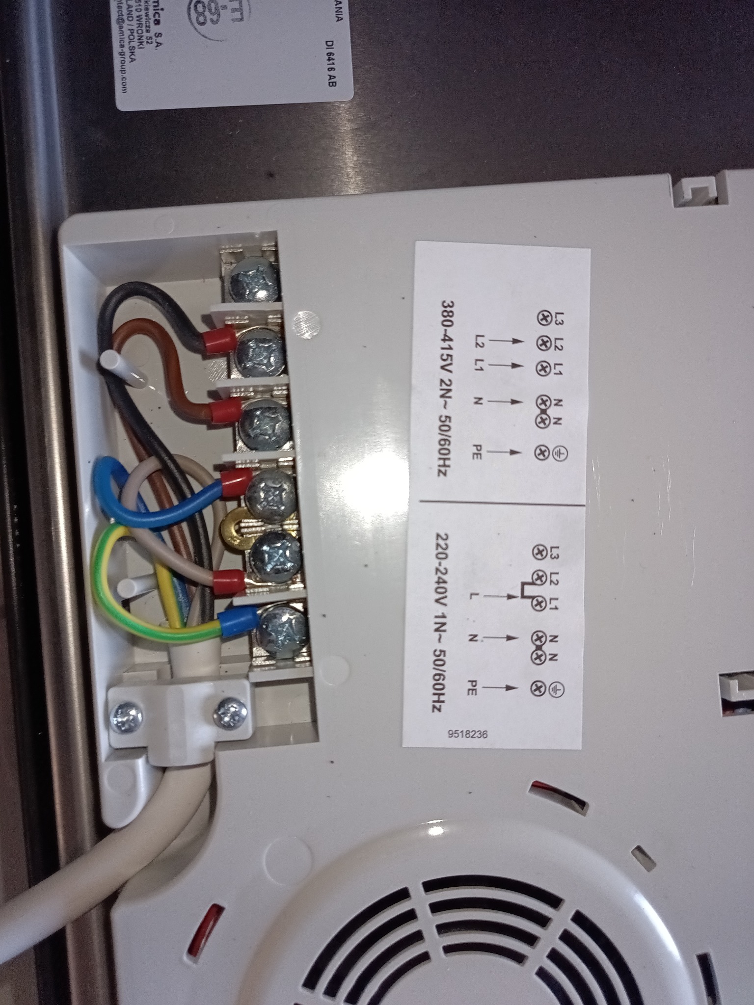 Podłączenie przewodów do płyty indukcyjnej w Kwiatkowie. Widoczne kolorowe kable podłączone do złączki. Etykieta z instrukcją podłączenia.