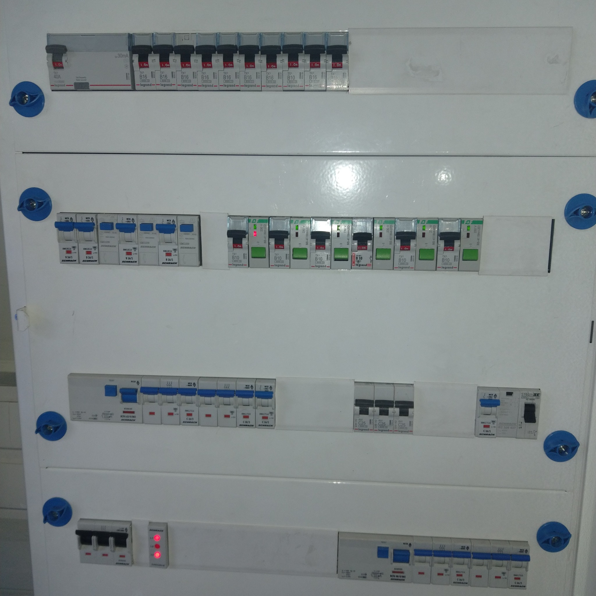 Rozdzielnia elektryczna z bezpiecznikami różnych producentów, widok z bliska, z widocznymi detalami i oznaczeniami.