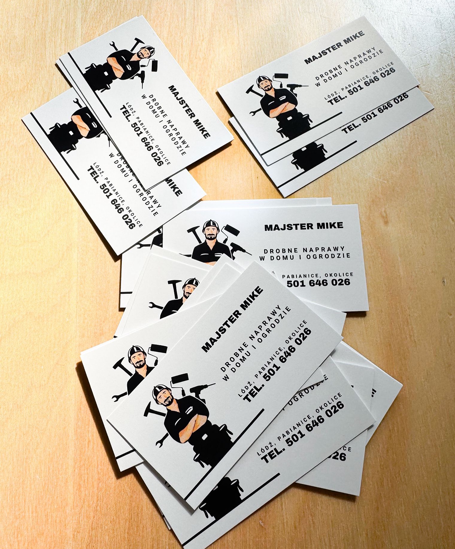 Wizytówki „Majster Mike” z ilustracją majstra i narzędzi, oferujące drobne naprawy w domu i ogrodzie, z danymi kontaktowymi: Łódź, Pabianice i numer telefonu.