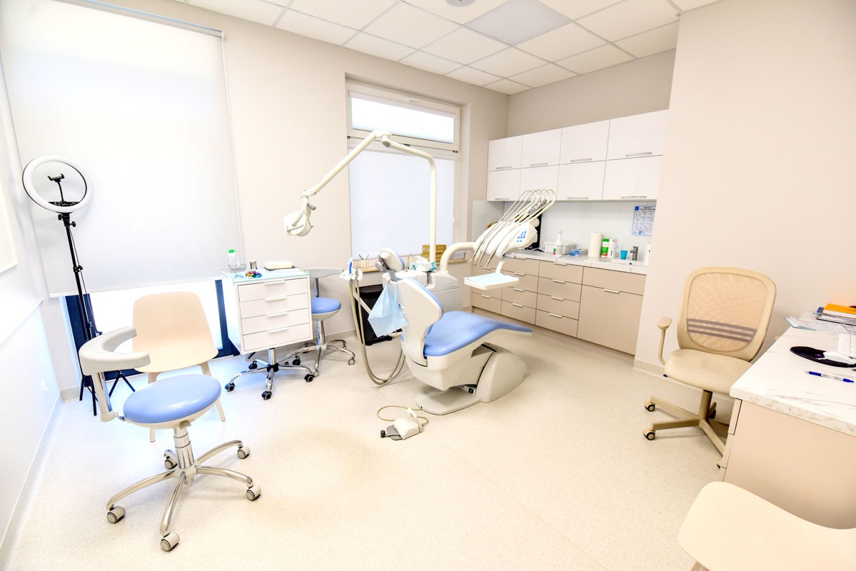 Jasne wnętrze gabinetu stomatologicznego z nowoczesnym fotelem dentystycznym w odcieniach błękitu, oświetleniem LED i minimalistycznymi meblami.