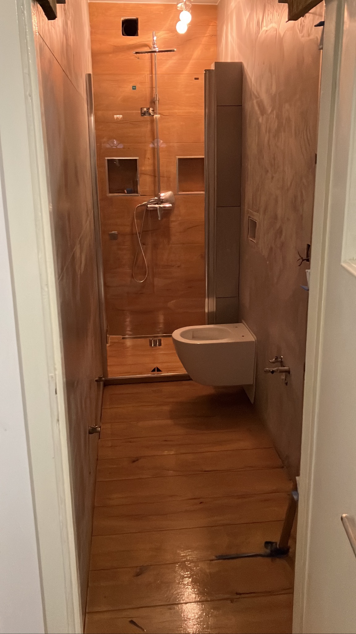 Nowoczesna łazienka z kabiną prysznicową typu walk-in i drewnianą podłogą w Cedyni. Ściany wykończone w odcieniach szarości i beżu, minimalistyczna armatura.