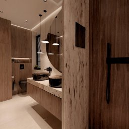 Design Atelier by Maria Słodowska - Nowoczesna łazienka z drewnianymi elementami, okrągłym lustrem i podświetlanymi półkami z kosmetykami. Dwie umywalki w kolorze czarnym.