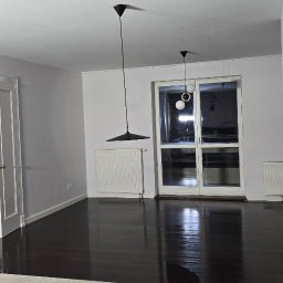 PLZ Painting And Decorating LTD - Jasne wnętrze po remoncie: świeżo pomalowane ściany w odcieniach szarości, ciemna podłoga, białe drzwi i okna. Minimalistyczne lampy wiszące.