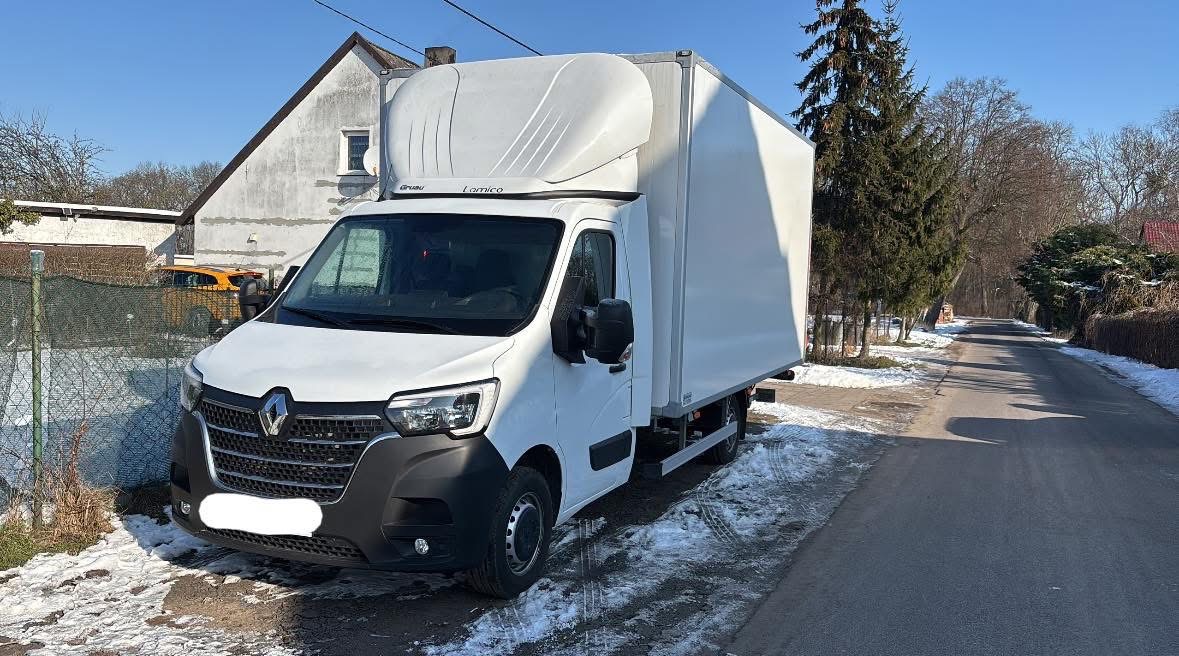 Biały Renault Master z zabudową kontenerową na tle zimowego krajobrazu i budynku. Widoczne logo Lamico na nadbudowie. Słoneczny dzień.