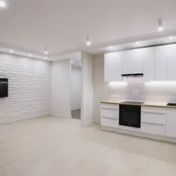 Nowoczesna, jasna kuchnia z białymi błyszczącymi szafkami i falistą ścianą z telewizorem. Minimalistyczny design, oświetlenie LED pod szafkami i punktowe na suficie.