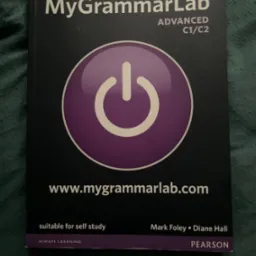 Podręcznik 'MyGrammarLab Advanced C1/C2' na ciemnym tle. Widoczny fioletowy symbol włącznika i adres strony internetowej. Książka do nauki języka angielskiego.
