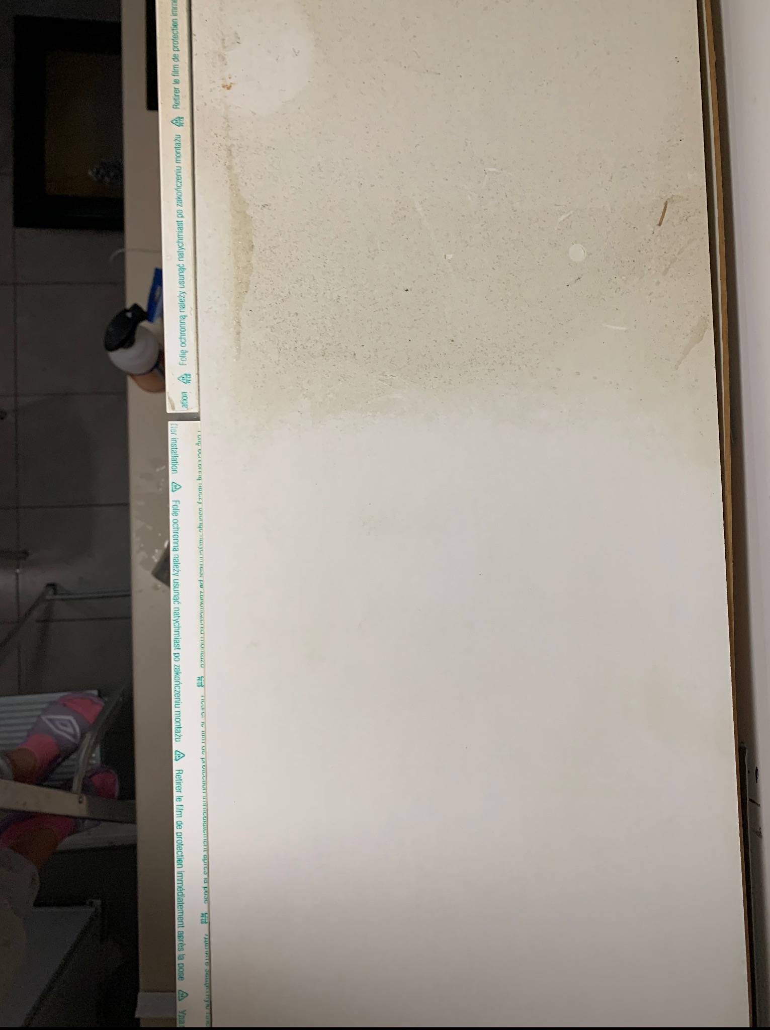 Okno po myciu, widoczna różnica w czystości. Górna część okna z zaciekami, dolna część czysta. Folia ochronna częściowo usunięta.