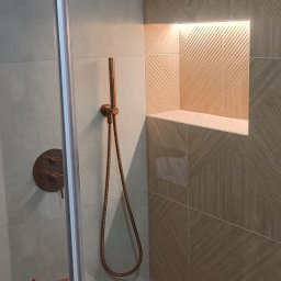 Piotr Najdowski - Nowoczesna kabina prysznicowa z miedzianą armaturą i wnęką w ścianie wyłożoną płytkami z subtelnym wzorem. Minimalistyczny design, stonowana kolorystyka.