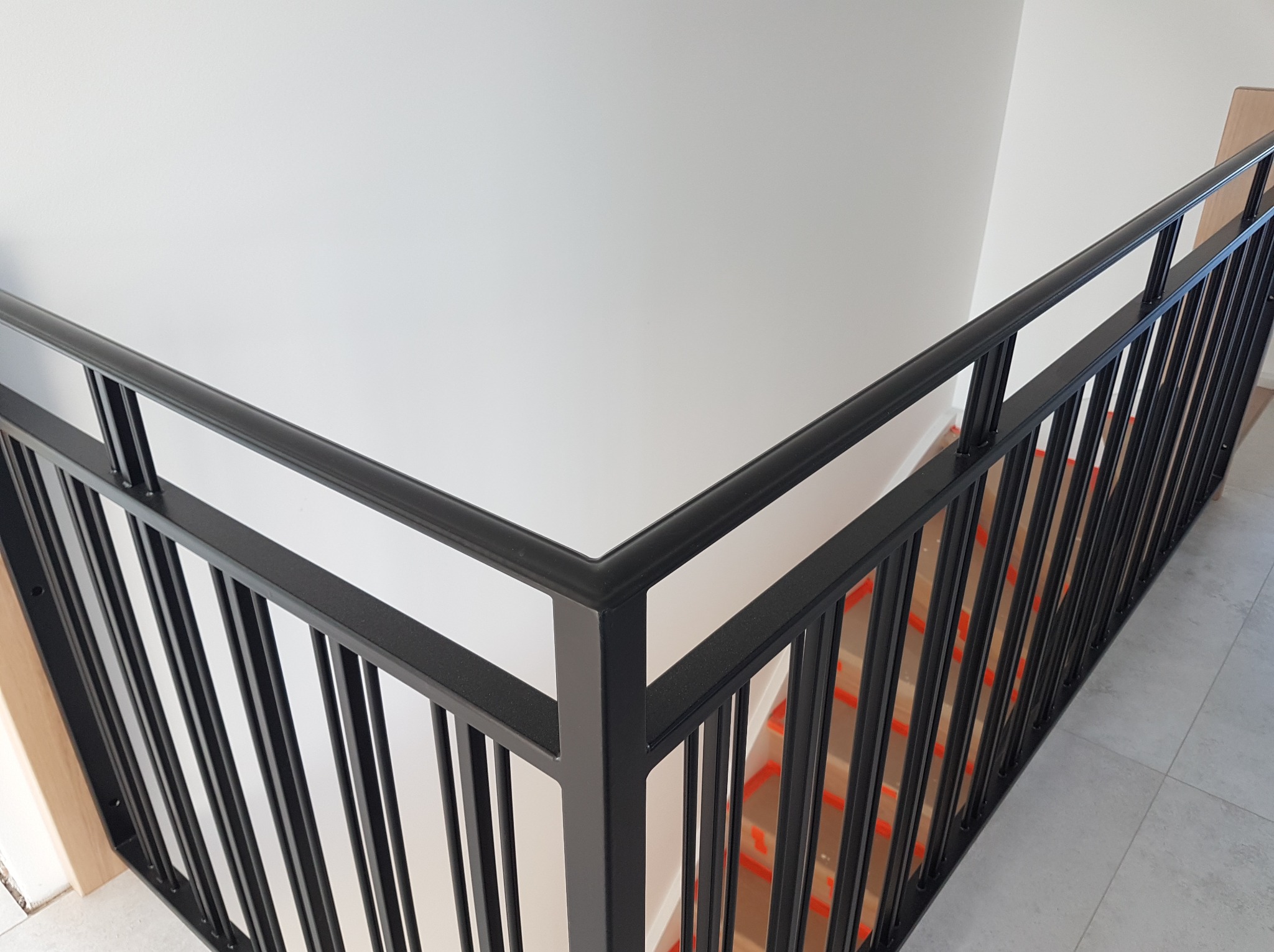 Nowoczesna, czarna balustrada metalowa przy schodach w Kotlin. Minimalistyczny design, gładkie wykończenie, widok z góry. Element wystroju wnętrza.