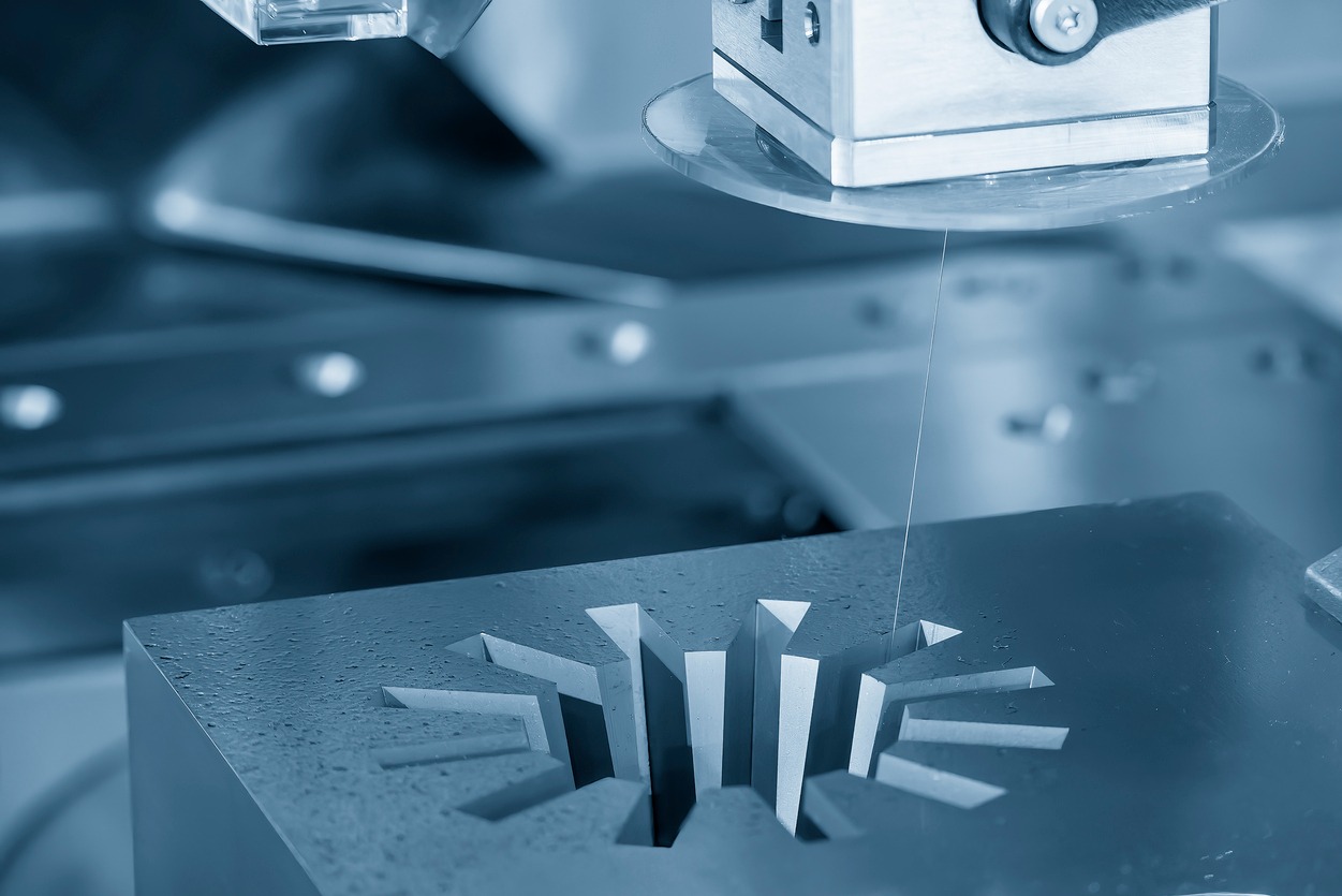 Precyzyjna obróbka elektroerozyjna CNC: Detal z wyciętymi rowkami w kształcie gwiazdy, obrabiany drutem. Chłodzenie cieczą, metal w odcieniach niebieskiego.