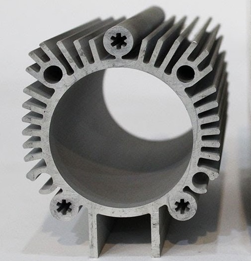 Aluminiowy profil radiatora o cylindrycznym kształcie z widocznymi żebrami chłodzącymi i otworami montażowymi. Precyzyjne wykonanie detali.