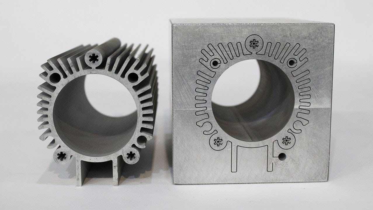 Aluminiowe elementy po precyzyjnej obróbce: radiator z żebrami i blok z wygrawerowanym wzorem, oba z otworem w środku. Jasne tło.