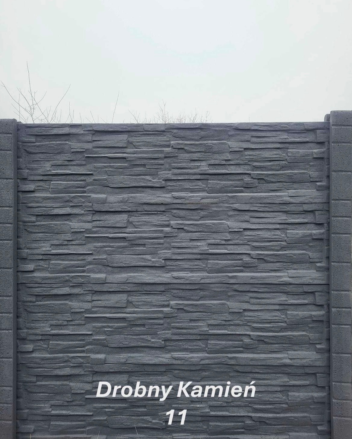 Szary, betonowy panel ogrodzeniowy o fakturze drobnego kamienia, z widocznymi słupkami po bokach. Na dole widoczny napis 'Drobny Kamień 11'.