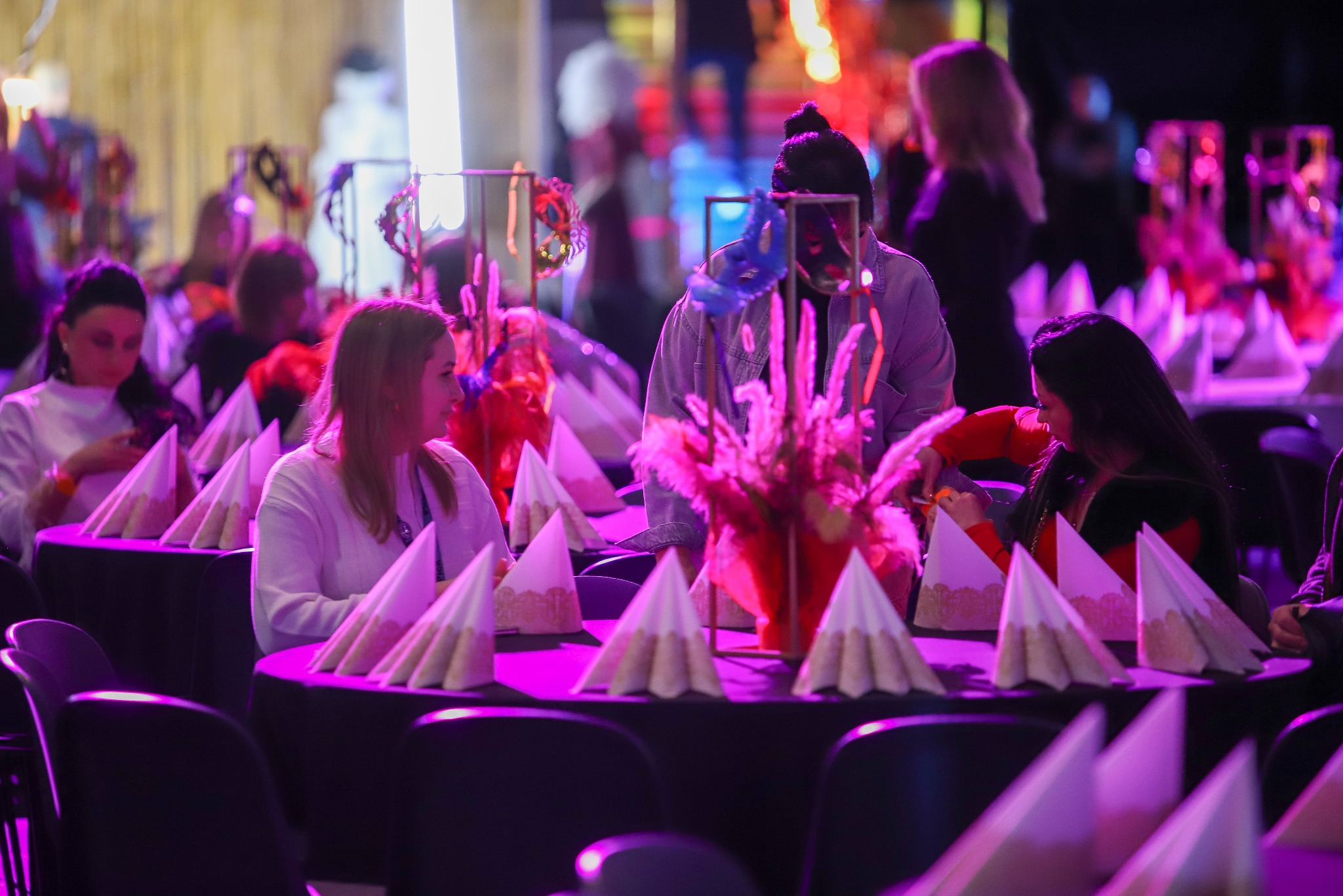 Uroczysty wystrój stołów z dekoracjami kwiatowymi i serwetkami w Mierzynie, oświetlony fioletowym światłem, przygotowany na imprezę.