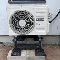 Energo-Tech Bednarczyk - Klimatyzator Hitachi, model R32, zamontowany na zewnątrz budynku w Ostrowi Mazowieckiej, widoczny przewód instalacyjny i podstawa montażowa.