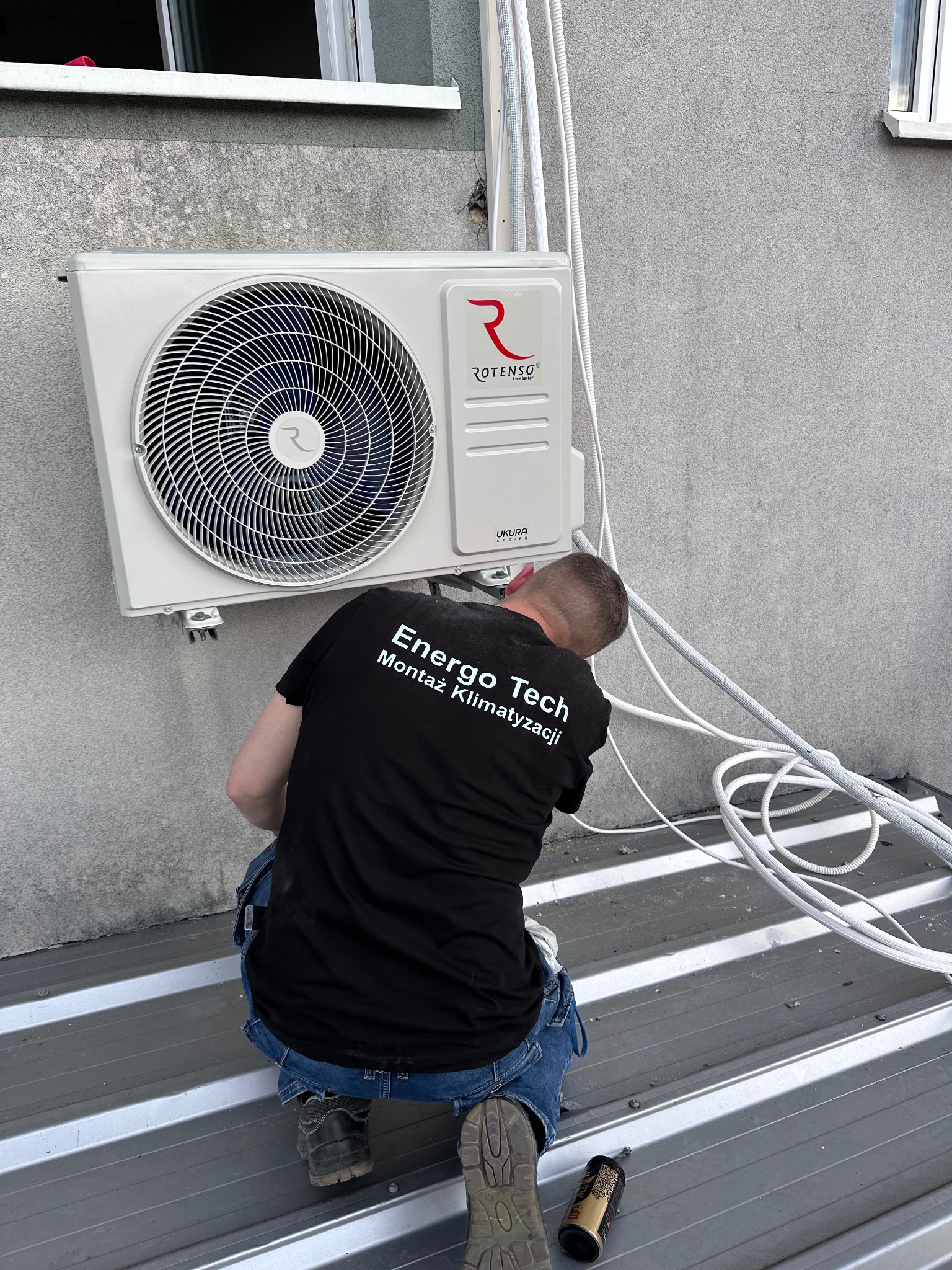 Montaż klimatyzacji Rotenso Ukura Series przez montera Energo Tech na zewnątrz budynku, widoczne przewody i narzędzia na metalowym dachu.