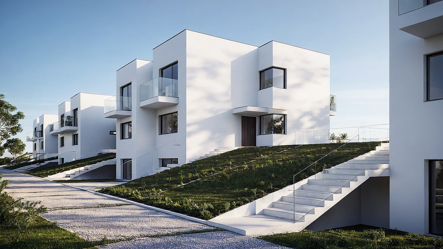 Minimalistyczne, białe domy szeregowe z balkonami i schodami na zboczu, oświetlone popołudniowym słońcem, z widoczną fakturą elewacji i otoczeniem z zielenią.