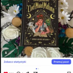 Książka Anety Jadowskiej 'Cud, Miód, Malina' na tle dekoracji z białych róż i zielonych liści, sfotografowana z góry. Widoczny kadr z Instagrama.