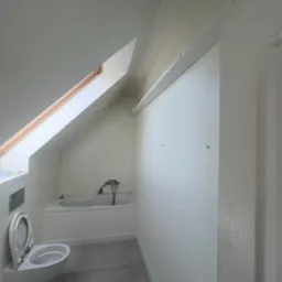 Biała łazienka na poddaszu z oknem dachowym, widok na wannę, toaletę i szarą podłogę. Ściany przygotowane pod malowanie, widoczne haczyki na ścianie.