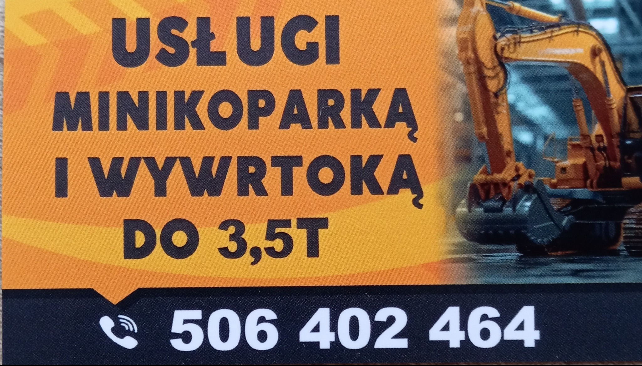 Pomarańczowo-czarny baner reklamowy z tekstem 'Usługi minikoparką i wywrotką do 3,5T' oraz numerem telefonu, obok grafika minikoparki.