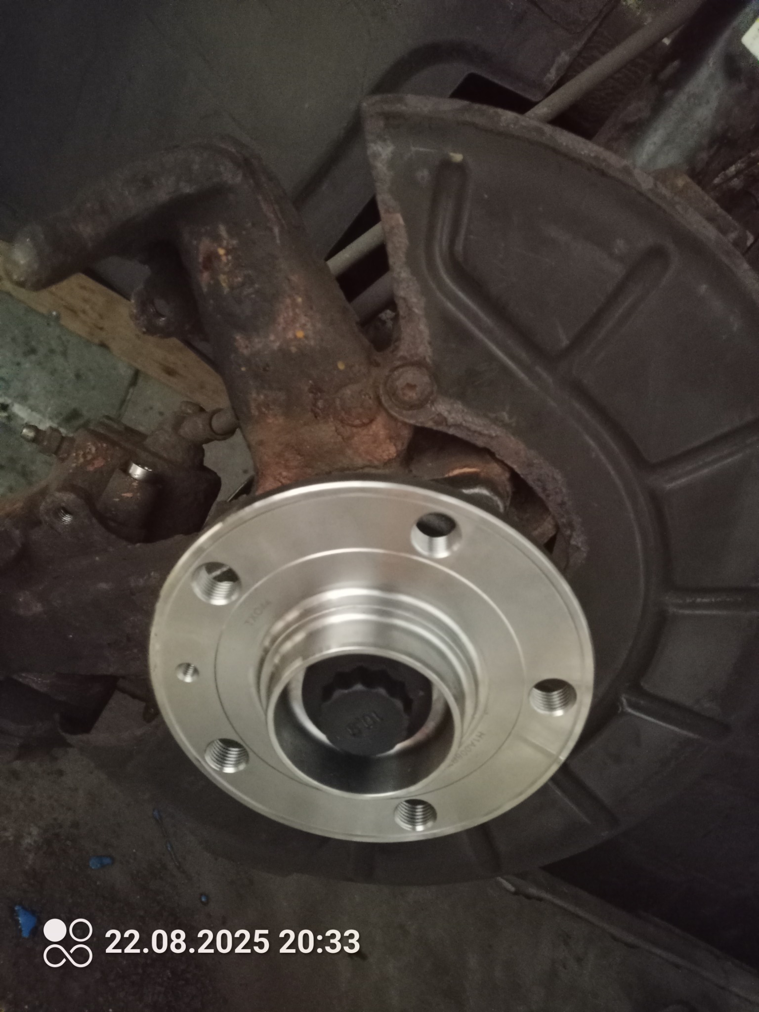 Piasta koła po wymianie, widoczne ślady korozji na elementach zawieszenia. Element układu hamulcowego w tle.