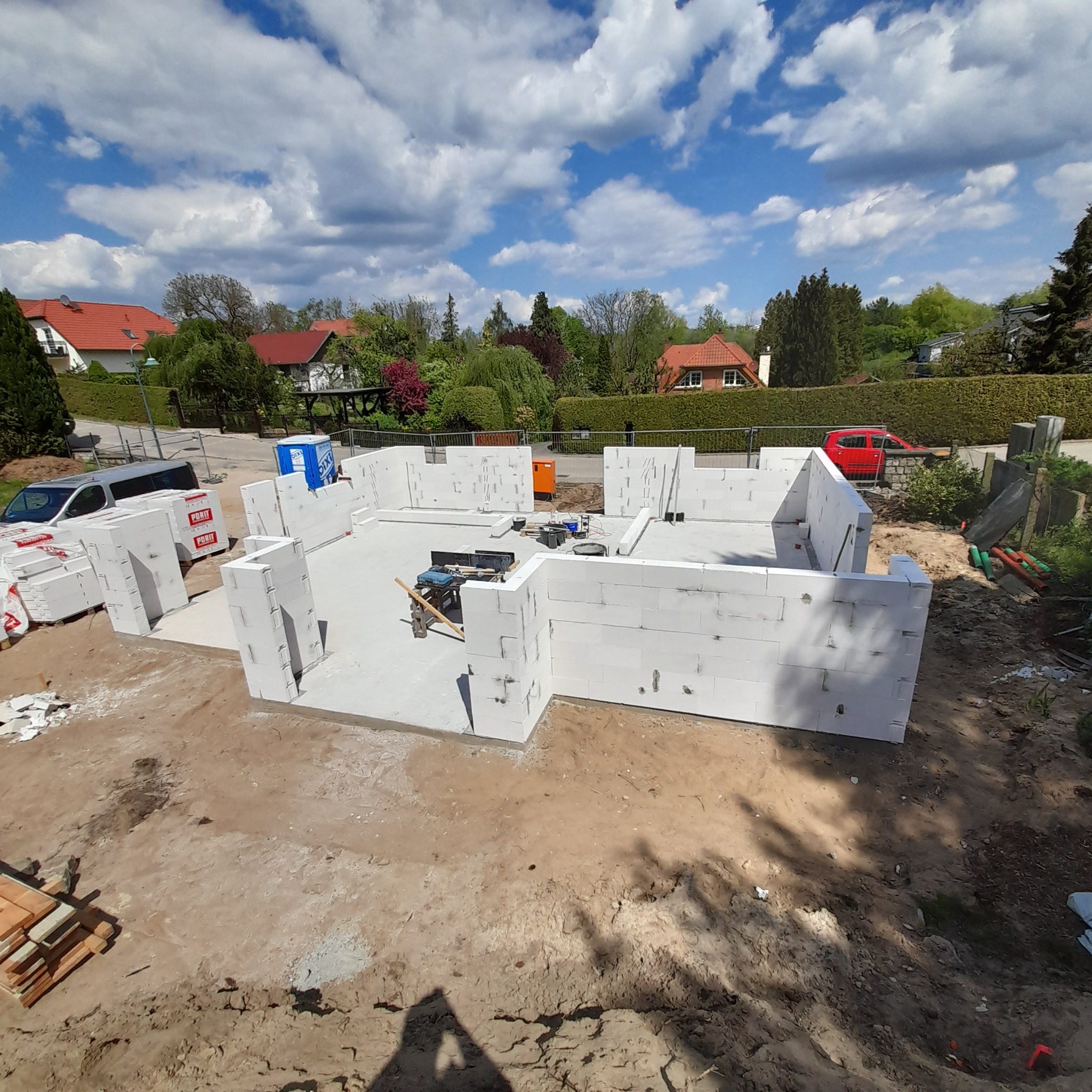 Wznoszenie ścian fundamentowych z bloczków PORIT w Pyrzycach. Widok z góry na rozpoczętą budowę domu jednorodzinnego, narzędzia pracy wewnątrz fundamentów.