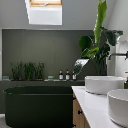 InHome AM - Stylowa łazienka w odcieniach zieleni z wolnostojącą wanną, roślinami i oknem dachowym, wykończona w nowoczesnym stylu z elementami drewnianymi.