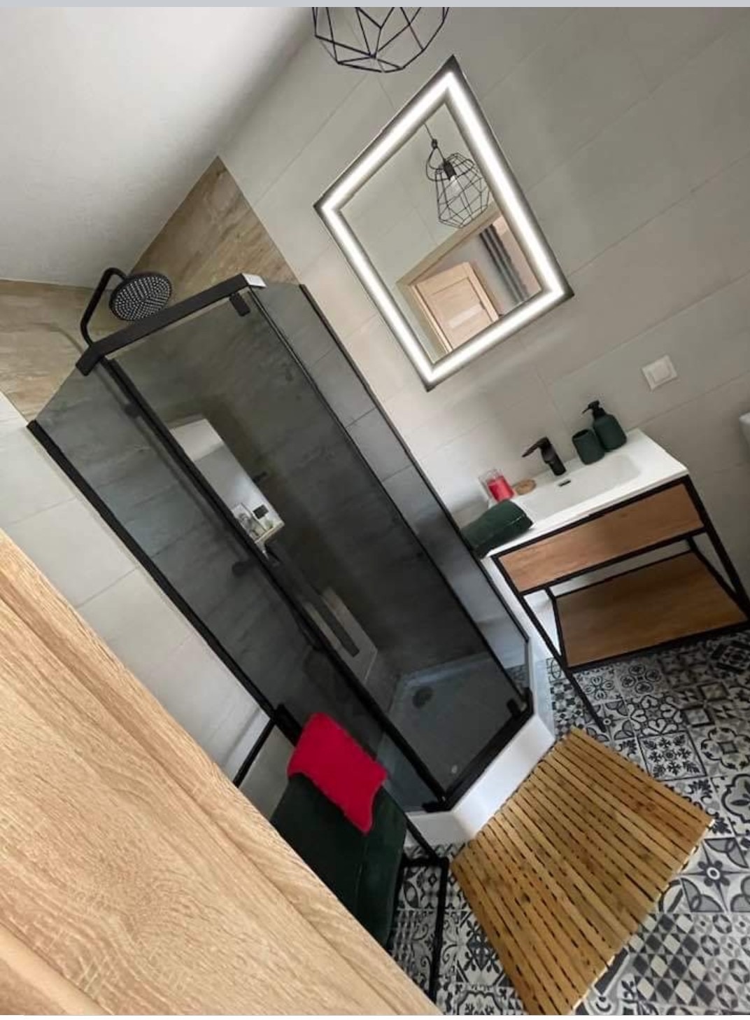 Nowoczesna łazienka z kabiną prysznicową typu walk-in, umywalką na drewnianym stelażu i podświetlanym lustrem. Czarno-biała mozaika na podłodze.