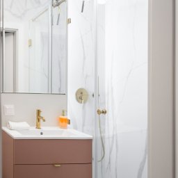 AP Budownictwo Agnieszka Lipińska - Nowoczesna łazienka z kabiną prysznicową i umywalką w kolorze pudrowego różu, złota armatura, białe marmurowe płytki. Minimalistyczny design.