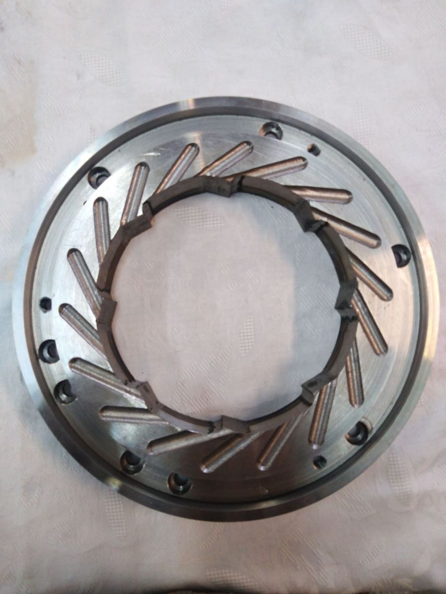 Metalowa tarcza z promieniście rozmieszczonymi elementami i wewnętrznym pierścieniem, widoczne ślady obróbki, precyzyjne wykonanie.