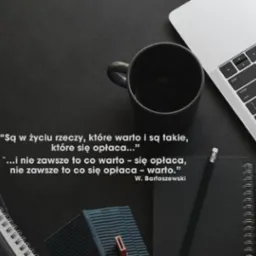 Minimalistyczne biurko z cytatem Bartoszewskiego, czarnym kubkiem, notatnikiem i laptopem. Stonowana kolorystyka i prosta kompozycja.