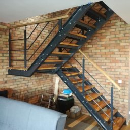 GREGOR-STAL mgr inż.Grzegorz Byczkowski - Loftowe schody z metalową konstrukcją i drewnianymi stopniami, umieszczone przy ceglanej ścianie w jasnym wnętrzu. Widoczny fragment sofy.