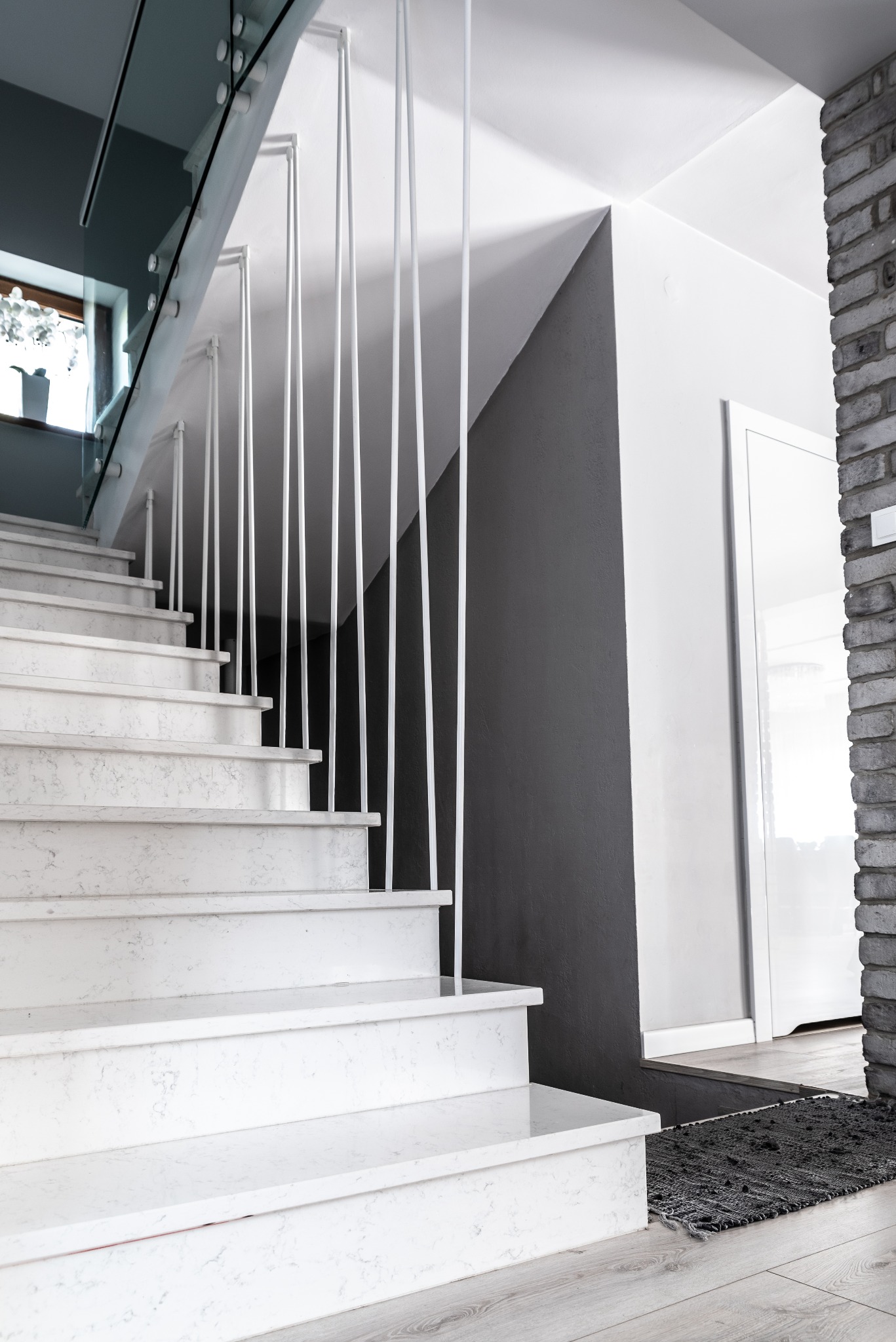 Nowoczesne schody z balustradą szklaną i metalowymi słupkami w Cienin Zaborny-Parcele. Marmurowe stopnie i minimalistyczny design.