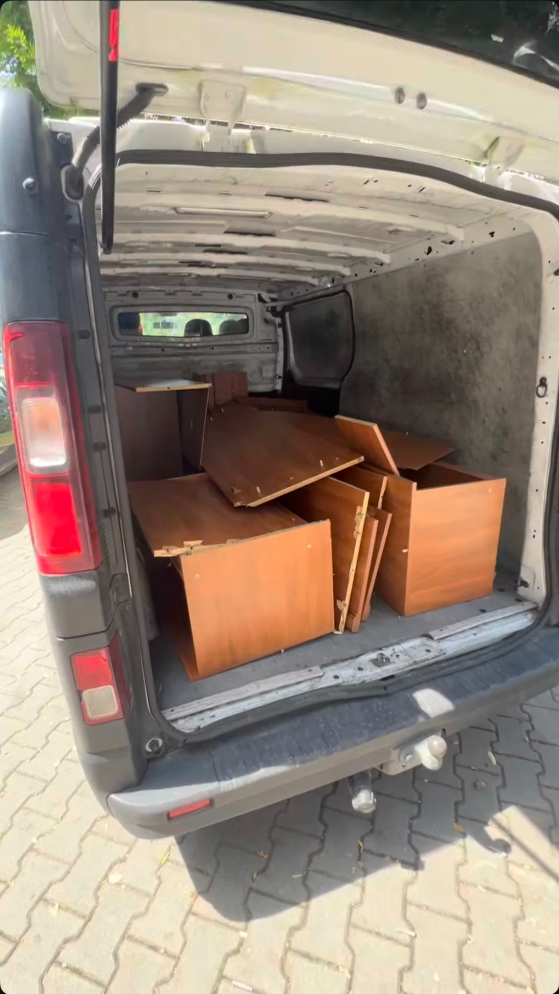 Wnętrze busa wypełnione elementami mebli w odcieniach brązu, przygotowanych do transportu. Widoczne płyty, półki i elementy konstrukcyjne.