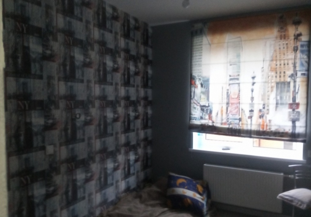 Pokój po remoncie w Warszawie: ściana z tapetą z motywem NY, roleta rzymska z widokiem miasta. Nowoczesny design wnętrza, przytulna atmosfera.