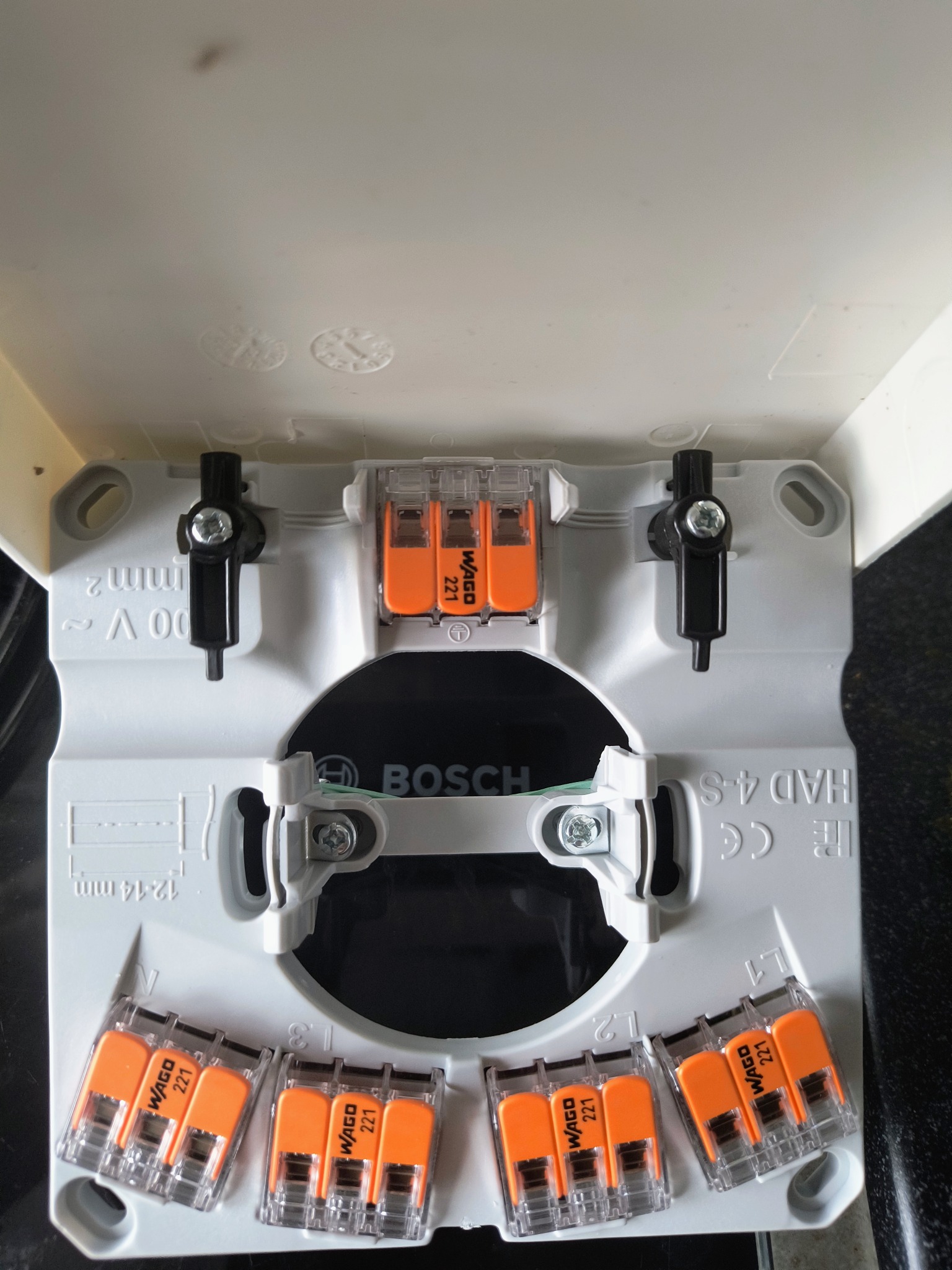 Szara puszka instalacyjna Bosch z pomarańczowymi złączkami Wago 221, widok z góry. Złączki rozmieszczone wewnątrz puszki, gotowe do podłączenia przewodów.