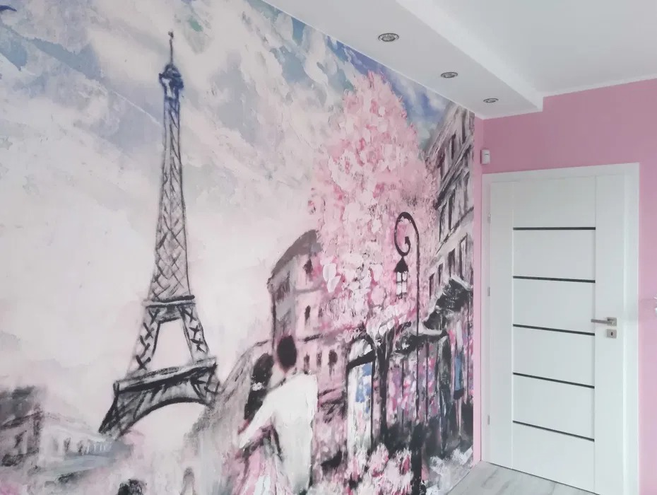 Białe drzwi wewnętrzne z poziomymi, czarnymi wstawkami na tle ściany z fototapetą z motywem Paryża i różowej ściany. Widok na fragment pokoju.