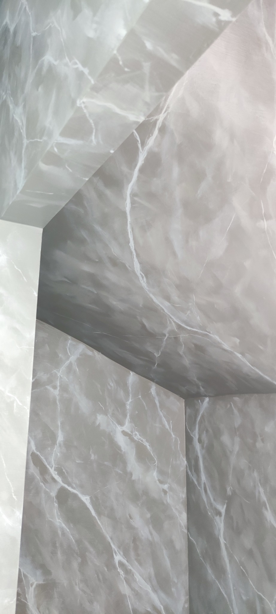 Szara ściana i sufit z efektem marmuru, delikatne białe żyłki, kąt ujęcia z dołu, widoczne łączenie powierzchni, nowoczesny design.