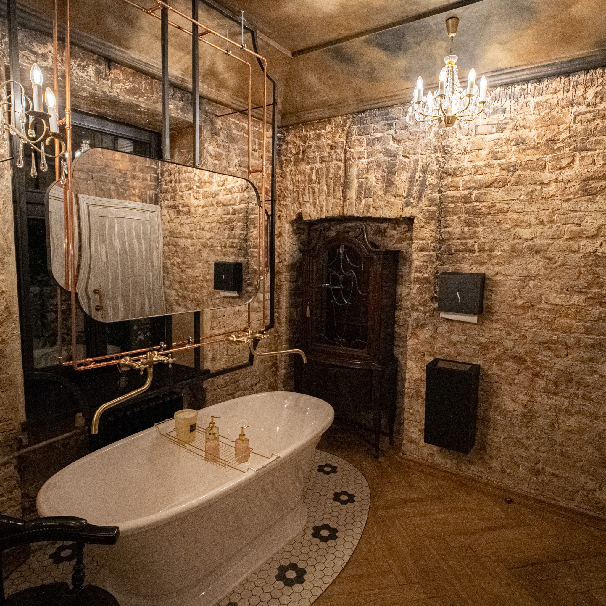 Stylowa łazienka z wanną wolnostojącą, ceglanymi ścianami i designerskim oświetleniem. Elementy instalacji miedzianej nadają unikalny charakter wnętrzu.