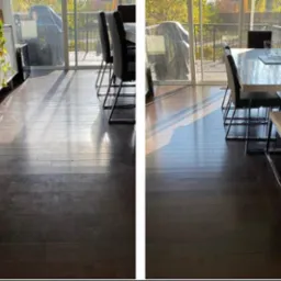 Porównanie: ciemna drewniana podłoga przed i po czyszczeniu. Po prawej stronie podłoga lśni, po lewej widoczne ślady użytkowania. Widoczne krzesła i stół.