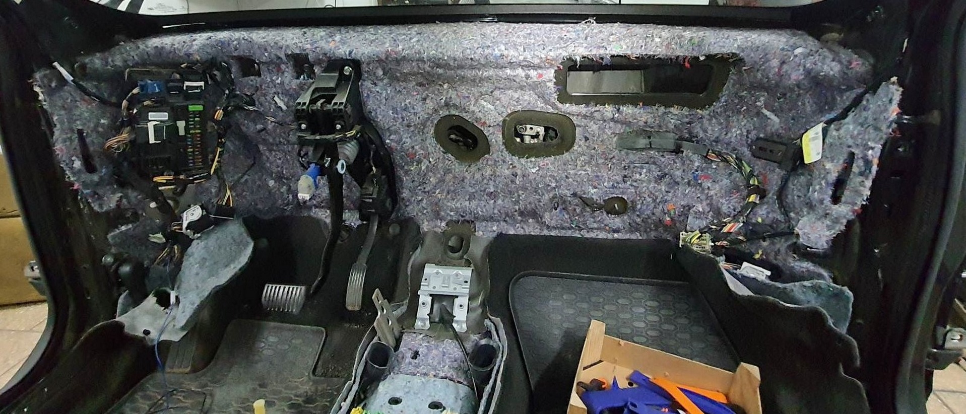 Wnętrze samochodu w trakcie demontażu deski rozdzielczej, widoczne przewody i elementy instalacji elektrycznej.