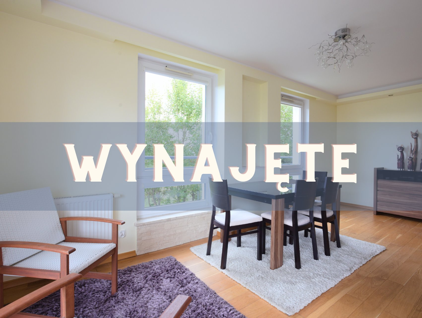 Jasne wnętrze z oknami, stołem i krzesłami. Na zdjęciu widnieje napis 'Wynajęte'.