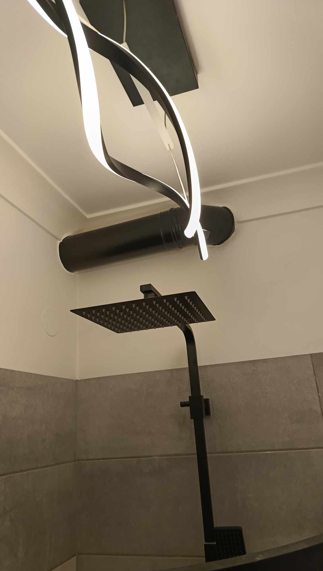 Nowoczesna kabina prysznicowa z deszczownicą i designerskim oświetleniem w łazience w Lublinie. Minimalistyczny styl, szara glazura, czarne elementy.