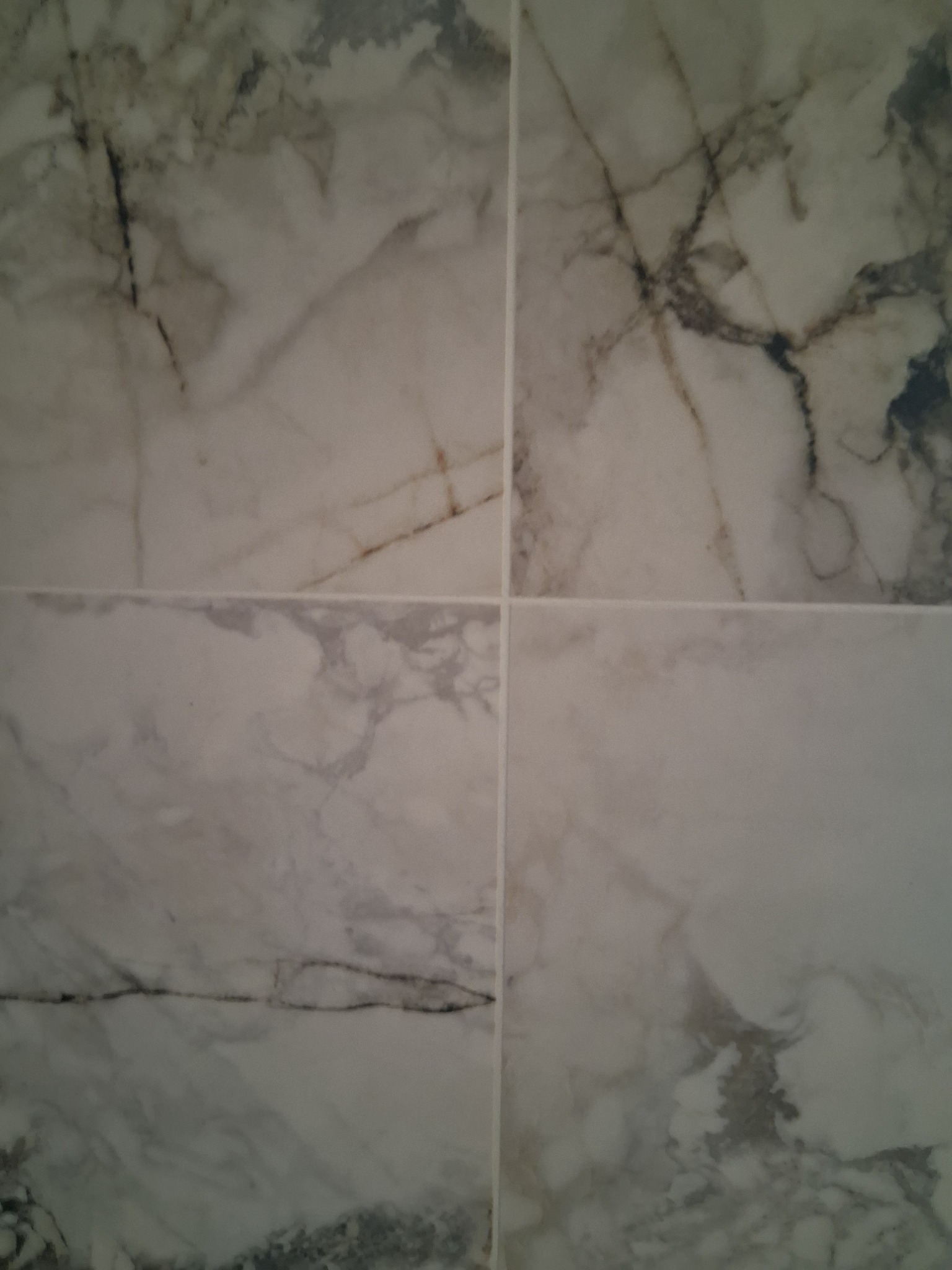 Cztery płytki imitujące marmur w odcieniach bieli i szarości, ułożone obok siebie, tworzą elegancką powierzchnię. Widoczne fugi podkreślają regularny wzór.